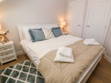 A bedroom with a bed cushions lamps and a rug at Driftwood Haven in Carbis Bay
