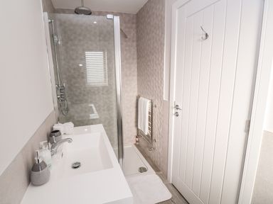 A bathroom with a sink countertop and a glass shower enclosure at Driftwood Haven in Carbis Bay