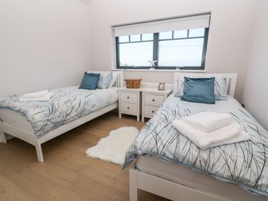 A bedroom with two single beds and a window between them at Driftwood Haven in Carbis Bay