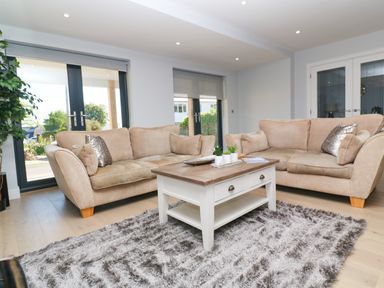 A living room with two beige sofas a wooden coffee table and a gray rug at Driftwood Haven in Carbis Bay