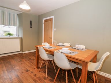 A dining room with a wooden table set for four and white chairs at Yr Hen Dy Capel in Blaenau Ffestiniog