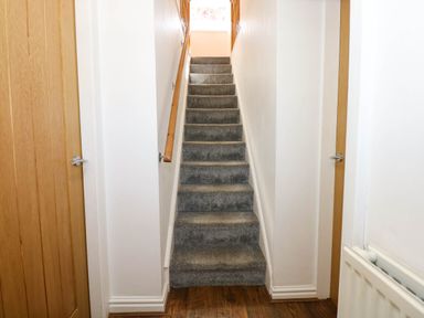 A carpeted staircase with wooden handrails between two wooden doors at Yr Hen Dy Capel in Blaenau Ffestiniog