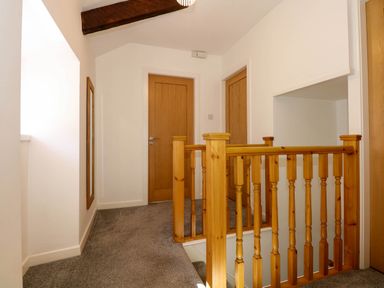 A hallway with carpeted floor wooden doors a stair railing and a wall mirror at Yr Hen Dy Capel in Blaenau Ffestiniog