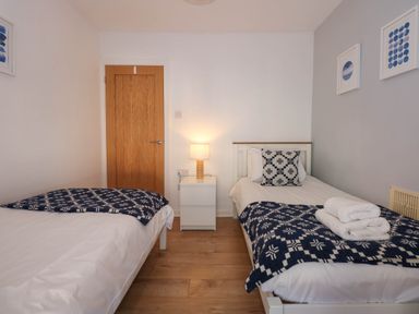 A bedroom with two single beds a nightstand with a lamp and framed pictures on the wall at Yr Hen Dy Capel in Blaenau Ffestiniog