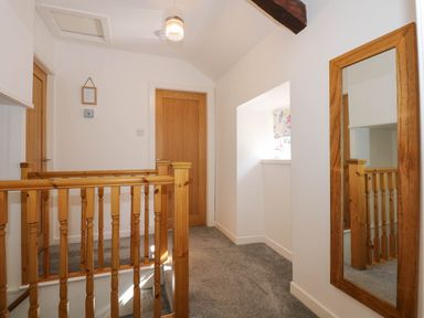 A hallway with wooden railings doors and a large wall mirror at Yr Hen Dy Capel in Blaenau Ffestiniog