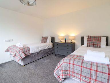 A bedroom with two beds and a nightstand at Glyn Morfa in Harlech
