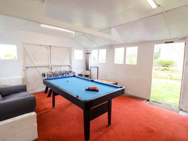 A game room with a pool table and a sofa at Glyn Morfa in Harlech