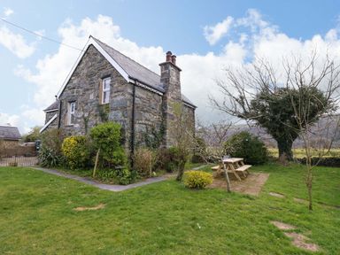 A stone house with a garden and a picnic table at Glyn Morfa in Harlech