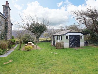 A garden with a shed and picnic table at Glyn Morfa in Harlech