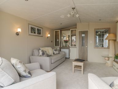 A living room with two sofas a small table a cabinet with glass doors and a door at The Sequoia in Cloughton