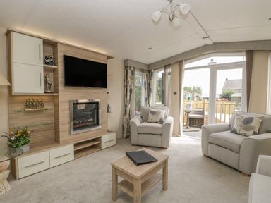 A living room with two armchairs a coffee table a wall-mounted television and a fireplace at The Sequoia in Cloughton