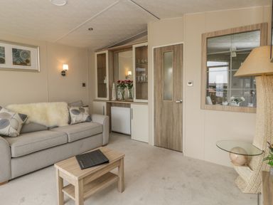 A living room with a sofa cushions a wooden coffee table and a wall unit with glass doors at The Sequoia in Cloughton