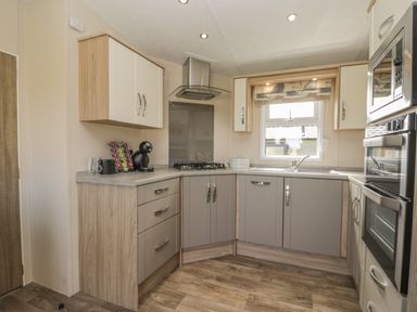 A kitchen with cabinets a gas stove a coffee machine and an oven at The Sequoia in Cloughton