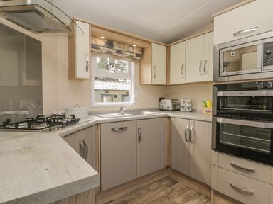 A kitchen with countertop stove oven microwave cabinets and a window at The Sequoia in Cloughton
