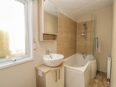 A bathroom with a sink and mirror cabinet next to a bathtub with a shower at The Sequoia in Cloughton