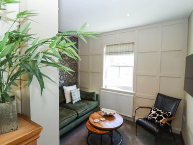 A sitting area with a green sofa and black chair around a wooden coffee table under a window at Gavel Cottage in Whitby