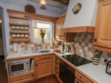 A kitchen with wooden cabinets and countertop at Cobbles House in Whitby