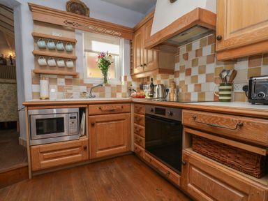 A kitchen with wooden cabinets and appliances at Cobbles House in Whitby