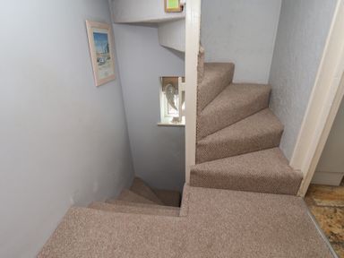 A staircase with carpet and a framed picture at Cobbles House in Whitby