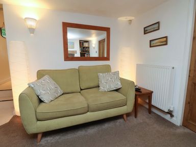 A living room with a sofa and a mirror at Damson Cottage in Whitby