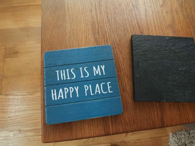 A blue coaster with text on a wooden table at Damson Cottage in Whitby