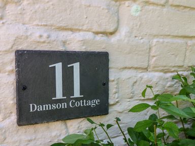 A house number and name plaque on a wall at Damson Cottage in Whitby