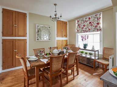 A dining room with a wooden table set for six people and wooden chairs at Harbour House in Whitby