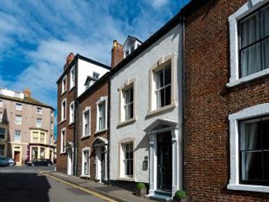 A street with brick and white houses and cars parked at Harbour House in Whitby