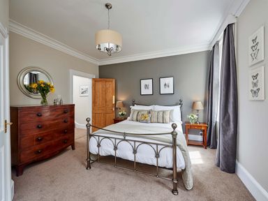 A bedroom with a metal bed frame a wooden dresser and two bedside tables at Harbour House in Whitby