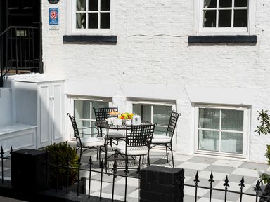 An outdoor patio area with a round metal table and four chairs with white cushions at Albany House Whitby