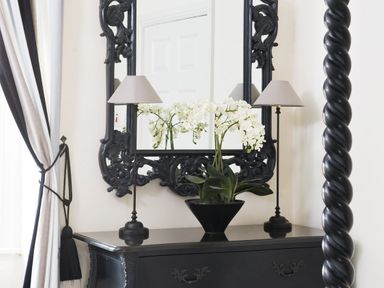 A black dresser with a decorative mirror wall lamps and a potted white orchid at Albany House Whitby