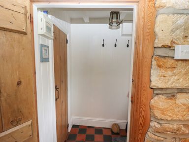 A small entryway with wooden door and three hooks on the wall at The Cottage in Sandsend