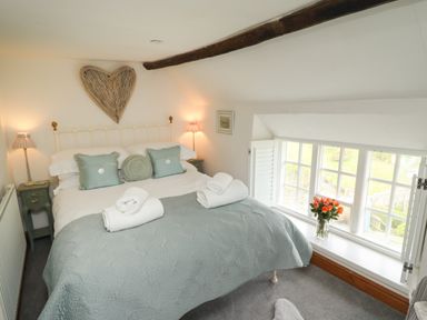 A bedroom with a bed with pillows and rolled towels near a window with flowers at The Cottage in Sandsend