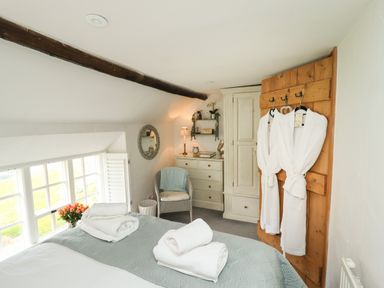 A bedroom with a bed with towels and robes hanging on a wooden door at The Cottage in Sandsend