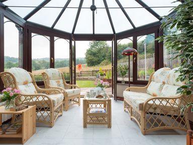 A conservatory with wicker furniture and floral cushions overlooking a garden at Seawinds in Robin Hood'S Bay