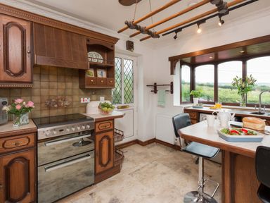 A kitchen with wooden cabinets a stove a table with chairs and a window overlooking greenery at Seawinds in Robin Hood'S Bay
