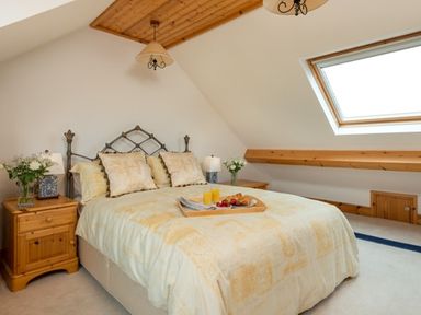 A bedroom with a double bed a skylight window wooden bedside tables with lamps and flower vases at Seawinds in Robin Hood S Bay