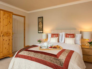A bedroom with a double bed a wooden wardrobe bedside tables with lamps and flowers at Seawinds in Robin Hood'S Bay