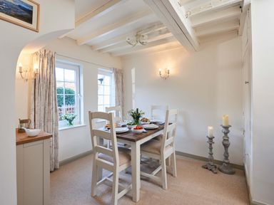 A dining room with a wooden dining table set with plates and candles at Rigg Cottage in Sandsend