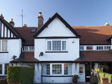 Front view of a white house with black trim a hedge and a potted plant at Rigg Cottage in Sandsend