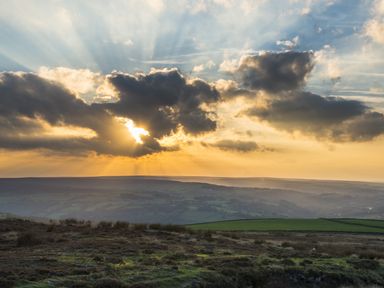 A landscape with fields and hills under a cloudy sky with sunlight at Esk View Cottage in Grosmont