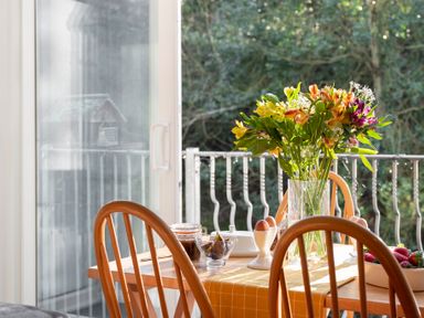 A dining table with flowers eggs and strawberries near a sliding glass door at Esk View Cottage in Grosmont
