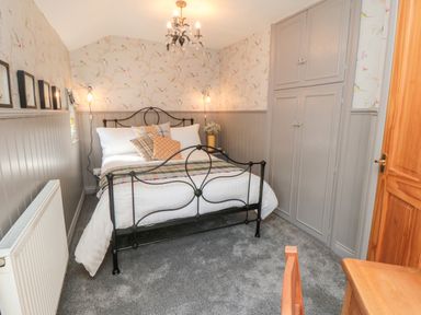 A bedroom with a metal bed frame pillows and wall cabinets at Esk View Cottage in Grosmont