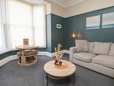 A sitting room with a beige sofa a round coffee table and a small dining table near a window at Church View in Whitby
