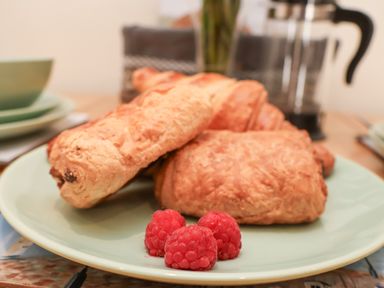 A plate with three croissants and three raspberries on a table with cups and a coffee press at Church View in Whitby