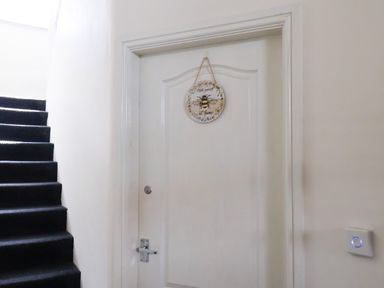 A white door with a hanging sign and black carpeted stairs beside it at Church View in Whitby