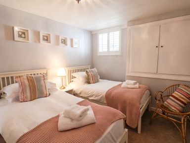A bedroom with two single beds a nightstand with a lamp and a wicker chair at Albany Cottage in Whitby