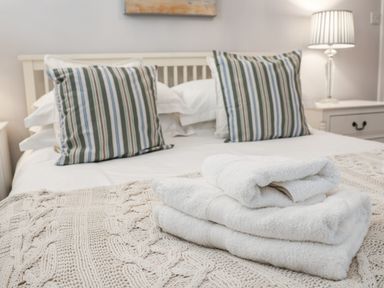 A bedroom with a bed with striped pillows and folded white towels on a knitted blanket at Albany Cottage in Whitby