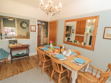 A dining room with a wooden table set for six people and a large mirror on the wall at Arden House in Whitby