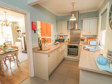 A kitchen with white cabinets a stove a sink countertop appliances and flowers at Arden House Whitby